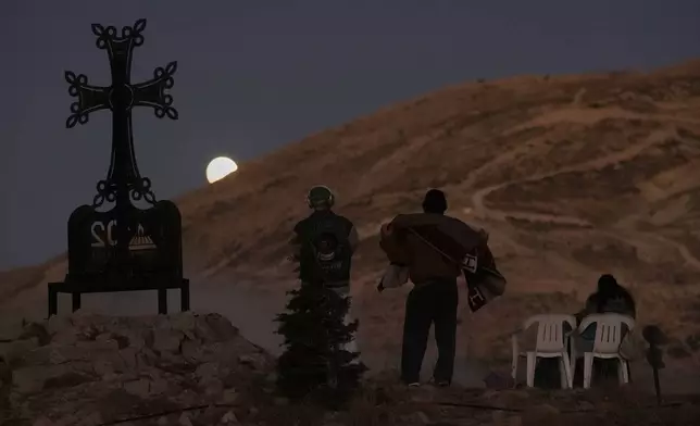 People watch as the moon shines during a total lunar eclipse over Kfardebian village, northeast of Beirut, Lebanon, Sunday, Sept. 7, 2025. (AP Photo/Bilal Hussein)