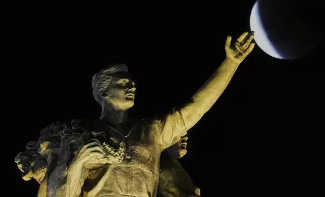 The full moon rises behind a sculpture atop of the central pavilion of the VDNKh, The Exhibition of Achievements of National Economy, during a total moon eclipse in Moscow, Russia, Sunday, Sept. 7, 2025. (AP Photo/Pavel Bednyakov)