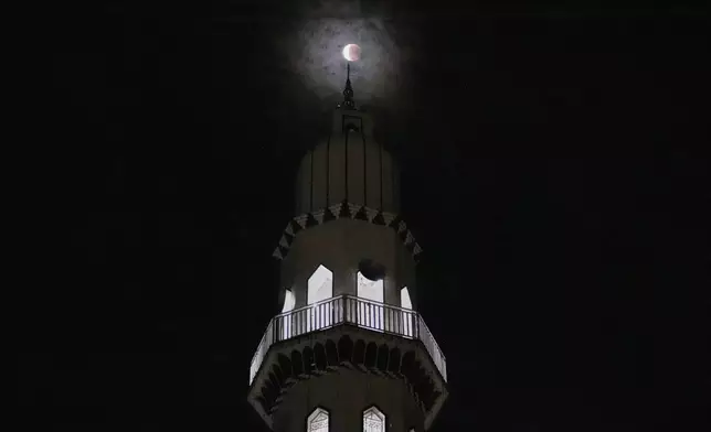 A partial lunar eclipse known as the blood moon, is seen through the minaret of a mosque in Rawalpindi, Pakistan, Monday, Sept. 8, 2025. (AP Photo/Anjum Naveed)
