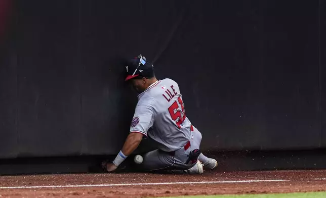 Washington Nationals outfielder Daylen Lile hits a wall while failing to catch a fly ball by New York Mets' Cedric Mullins during the third inning of a baseball game against the New York Mets, Sunday, Sept. 21, 2025, in New York. (AP Photo/Yuki Iwamura)