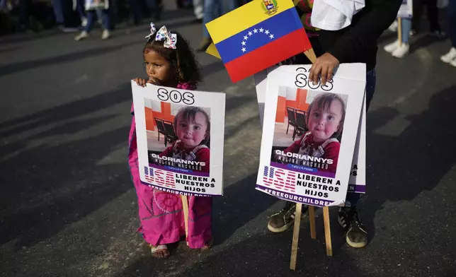 FILE - People hold signs with images of children in U.S. custody whose parents were deported, at a government-organized rally in Caracas, Venezuela, July 10, 2025. (AP Photo/Ariana Cubillos, File)