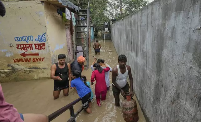 Residents wade through floodwater after the river Yamuna, swollen by incessant rain in the higher regions, overran its banks, in New Delhi, India, Tuesday, Sept. 2, 2025. (AP Photo/Manish Swarup)