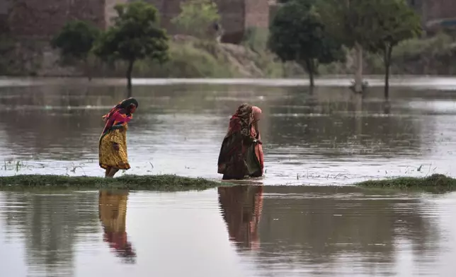 Women wade through a flooded area on the outskirts of Multan, Pakistan, Tuesday, Sept. 2, 2025. (AP Photo/Asim Tanveer)
