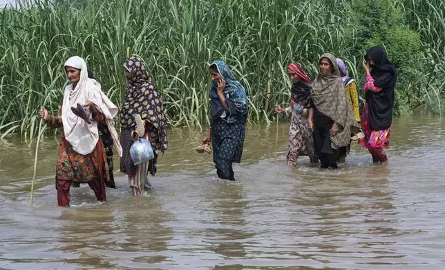 Women wade through a flooded field in Muza Islam Wala, in Jhang district, Pakistan, Tuesday, Sept. 2, 2025. (AP Photo/K.M. Chaudary)