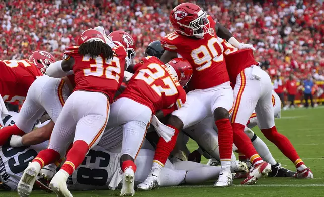 Kansas City Chiefs linebacker Nick Bolton (32), safety Chamarri Conner (27) and defensive end Charles Omenihu (90) try to stop a tush push by the Philadelphia Eagles late in the second half of an NFL football game Sunday, Sept. 14, 2025, in Kansas City, Mo. (AP Photo/Reed Hoffmann)