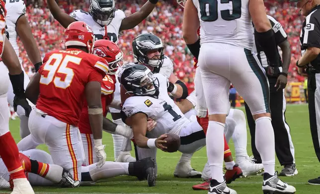 Philadelphia Eagles quarterback Jalen Hurts (1) is helped up by center Cam Jurgens, center back, after scoring a touchdown on a tush push late in the second half of an NFL football game against the Kansas City Chiefs, Sunday, Sept. 14, 2025, in Kansas City, Mo. (AP Photo/Reed Hoffmann)