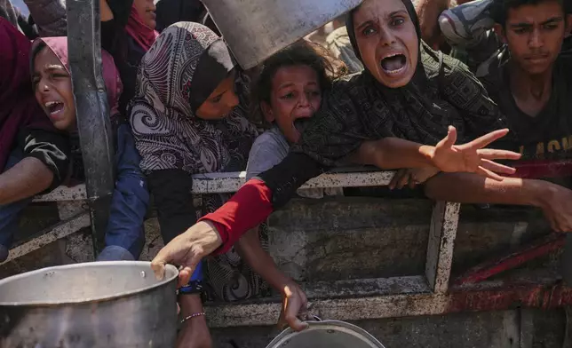Palestinians struggle to get donated food at a community kitchen in Gaza City, northern Gaza Strip, Aug. 4, 2025. (AP Photo/Jehad Alshrafi)