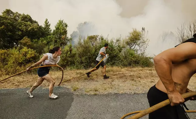 Local residents and volunteers work together to put out an encroaching wildfire in Larouco, northwestern Spain, Aug. 13, 2025. (AP Photo/Lalo R. Villar)