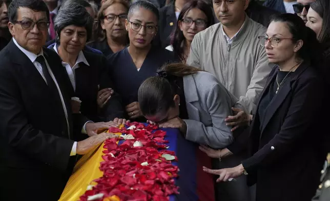 Police Maj. Adriana Pinzon kisses the coffin of her husband, Capt. Francisco Merchan, a police pilot killed when his helicopter was shot down by a dissident faction of the former FARC guerrilla group, as his father, Bernardo Merchan, and other relatives attend his burial in Mongua, Colombia, Aug. 25, 2025. (AP Photo/Fernando Vergara)