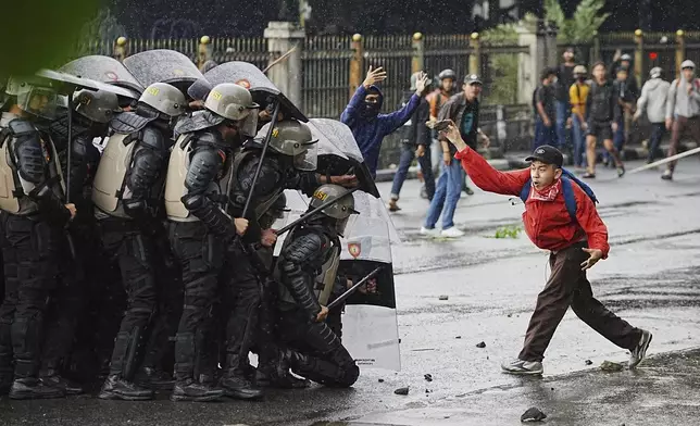 A demonstrator throws a rock at police during a protest against lavish allowances given to parliament members in Jakarta, Indonesia, Aug. 28, 2025. (AP Photo/Achmad Ibrahim)