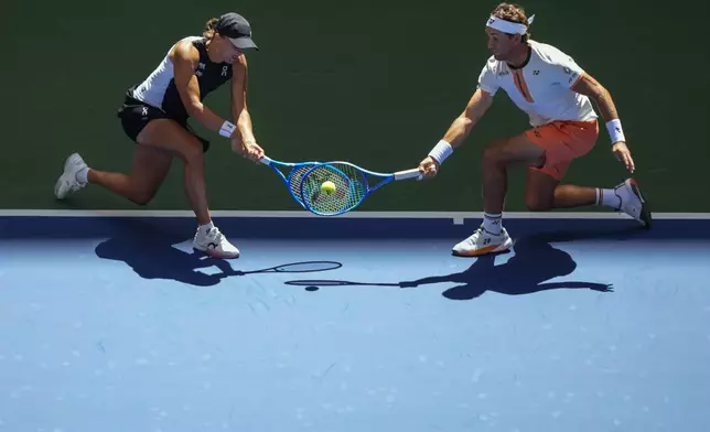 Norway's Casper Ruud, right, plays a shot as partner, Poland's Iga Swiatek, covers during their mixed doubles match at the U.S. Open tennis championships in New York, Aug. 19, 2025. (AP Photo/Yuki Iwamura)