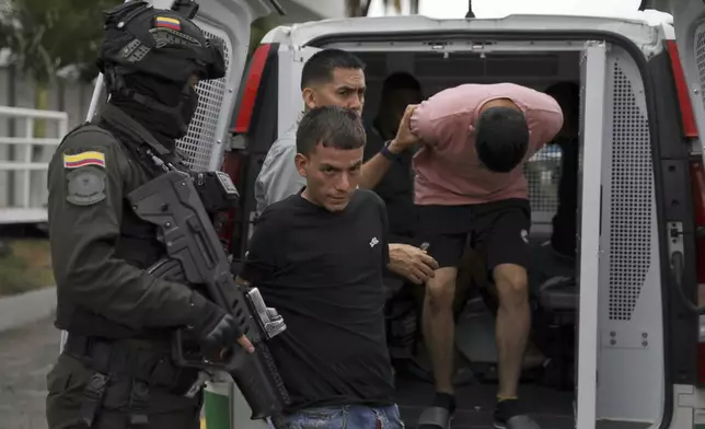 Police escort two arrested suspects in the detonation of a car bomb at an Air Force base to police headquarters in Cali, Colombia, Aug. 25, 2025. (AP Photo/Santiago Saldarriaga)