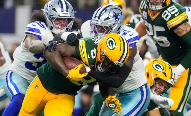 Green Bay Packers' Josh Jacobs (8) is stopped after a short gain by Dallas Cowboys defensive end Donovan Ezeiruaku (41) in the second half of an NFL football game Sunday, Sept. 28, 2025, in Arlington, Texas. (AP Photo/Jeffrey McWhorter)