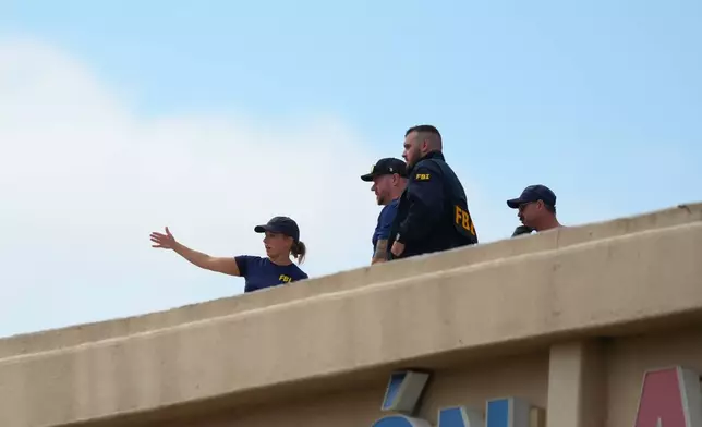 Law enforcement agents look around the roof of an apartment building near the scene of a shooting at a U.S. Immigration and Customs Enforcement office in Dallas on Wednesday, Sept. 24, 2025. (AP Photo/Julio Cortez)