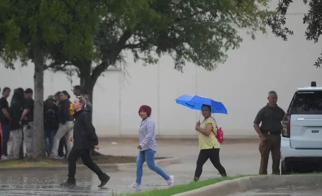 People gather with police at a staging area near a U.S. Immigration and Customs Enforcement office after a reported shooting, in Dallas on Wednesday, Sept. 24, 2025. (AP Photo/Julio Cortez)