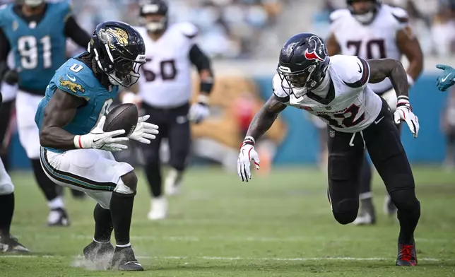 Jacksonville Jaguars linebacker Devin Lloyd, left, collects a fumble by Houston Texans wide receiver Nico Collins, right, during the second half of an NFL football game Sunday, Sept. 21, 2025, in Jacksonville, Fla. (AP Photo/Phelan M. Ebenhack)