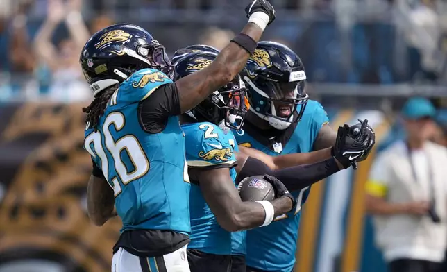 Jacksonville Jaguars cornerback Jourdan Lewis, center, celebrates an interception with teammates safety Antonio Johnson (26) and defensive end Josh Hines-Allen during the second half of an NFL football game against the Houston Texans Sunday, Sept. 21, 2025, in Jacksonville, Fla. (AP Photo/John Raoux)