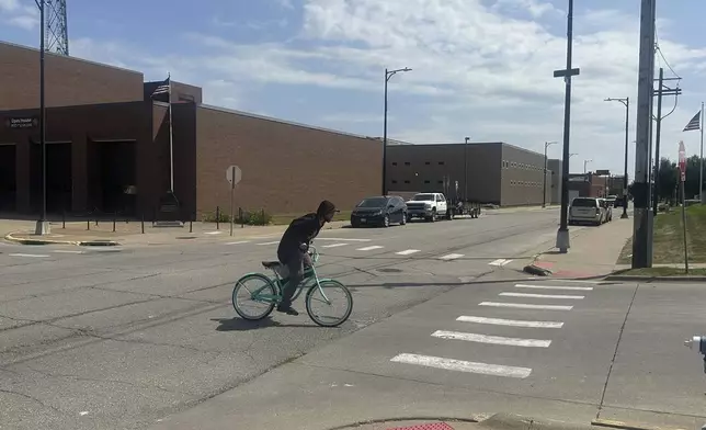 A cyclist crosses an intersection, on Monday, Sept. 8, 2025, where witnesses found Felipe de Jesus Hernandez Marcelo covered in blood after he was shot on June 21, in Muscatine, Iowa. (AP Photo/Ryan J. Foley)