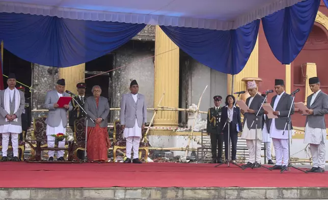 Nepalese President Ram Chandra Poudel, second from left, flanked by new Prime Minister Sushila Karki, third from left, attend an oath swearing ceremony for ministers, right, in front of the presidential building vandalized during recent protests, in Kathmandu, Nepal, Monday, Sept. 15, 2025. (AP Photo/Niranjan Shrestha)