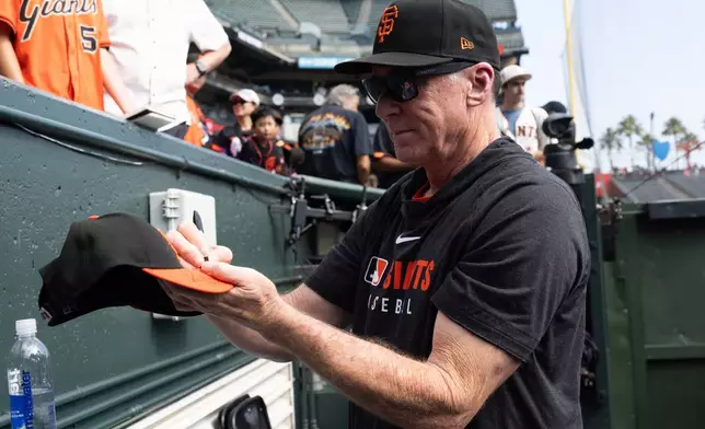 San Francisco Giants manager Bob Melvin gives out autographs before an MLB baseball game against the Colorado Rockies, Saturday, Sept. 27, 2025, in San Francisco. (AP Photo/Benjamin Fanjoy)