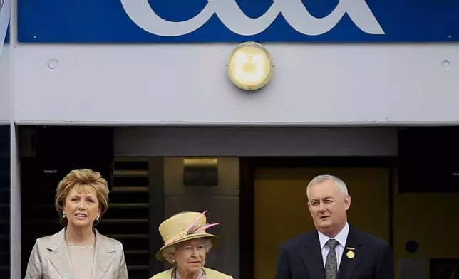 FILE - Britain's Queen Elizabeth II, centre, Irish President Mary Mc Aleese, left and Christy Cooney, President of the Gaelic Athletic Association look out at the pitch at the home of the GAA, Croke Park Stadium, in Dublin, Wednesday May 18, 2011. (AP Photo/Peter Morrison, File)