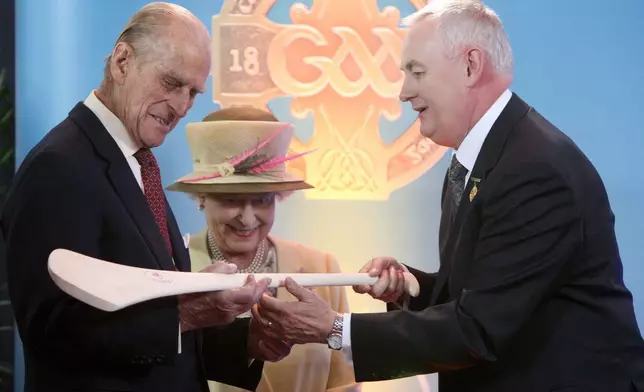 FILE - Britain's Queen Elizabeth II and her husband Prince Philip, Duke of Edinburgh, admire a hurley passed to them by the President of the Gaelic Athletic Association, Christy Cooney, during a tour of Croke Park, Dublin, during the second day of their state visit to Ireland. (Pool Photo via AP, File)