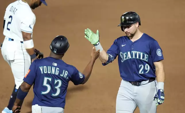 Seattle Mariners' Cal Raleigh (29) celebrates his single off Tampa Bay Rays pitcher Shane Baz with first base coach Eric Young Jr. (53) during the sixth inning of a baseball game Monday, Sept. 1, 2025, in Tampa, Fla. (AP Photo/Chris O'Meara)