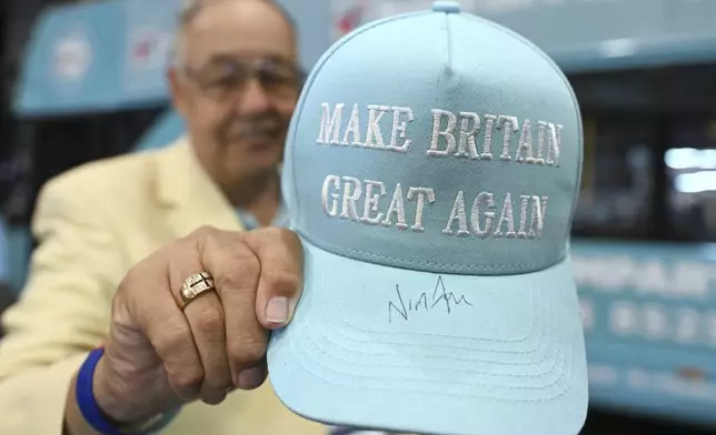 A member of the party shows his hat signed by Nigel Farage during the Reform party's annual conference at the National Exhibition Centre in Birmingham, England, Saturday, Sept. 6, 2025.(AP Photo/Thomas Krych)