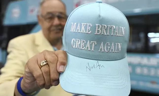 A member of the party shows his hat signed by Nigel Farage during the Reform party's annual conference at the National Exhibition Centre in Birmingham, England, Saturday, Sept. 6, 2025.(AP Photo/Thomas Krych)