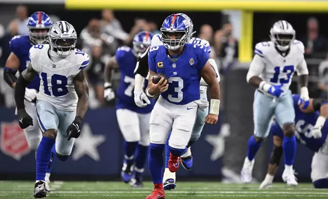 New York Giants quarterback Russell Wilson (3) runs the ball for a gain in the second half of an NFL football game as Dallas Cowboys' Damone Clark (18) gives chase Sunday, Sept. 14, 2025, in Arlington, Texas. (AP Photo/Jerome Miron)