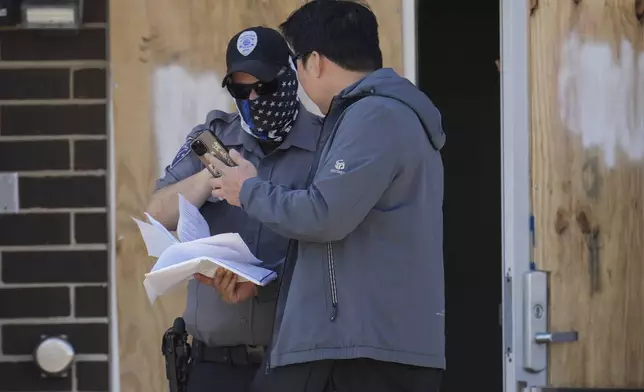 A person talks to a masked guard at the entrance of an immigration processing center Monday, Sept. 8, 2025, in Broadview, Ill., a suburb of Chicago. (AP Photo/Carolyn Kaster)