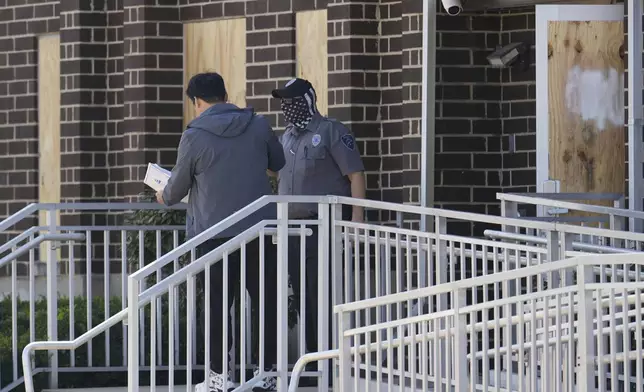A person talks to a masked guard at the entrance of an immigration processing center Monday, Sept. 8, 2025, in Broadview, Ill., a suburb of Chicago. (AP Photo/Carolyn Kaster)