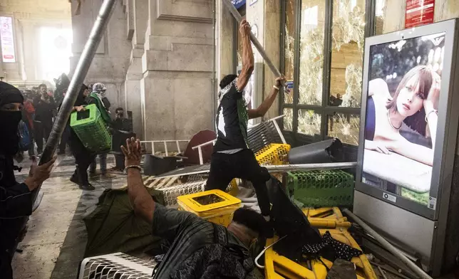Protesters enter Central Station during clashes with police after the strike march in support of Palestine, in Milan, Italy, Monday, Sept. 22, 2025. (Marco Ottico/Lapresse via AP)