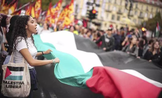 Demonstrators chant slogans as they hold a giant Palestinian flad during a nationwide transport, port, and school strike to protest against the war in Gaza, in Rome, Monday, Sept. 22, 2025. (Marco Alpozzi/LaPresse via AP)