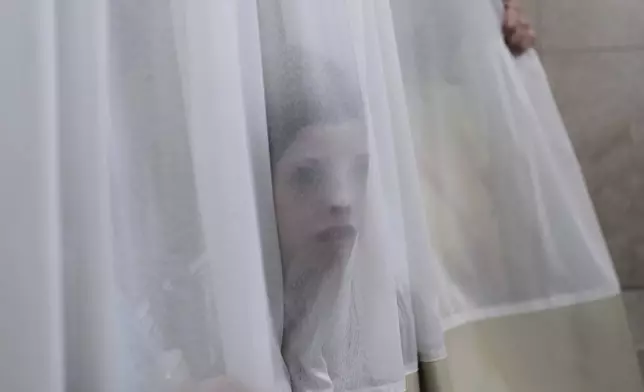 A mourner looks trough a curtain during the funeral of Levi Yitzhak Pash, who was killed along with five other Israelis in a shooting attack by two Palestinian gunmen at a bus stop in Jerusalem Monday, Sept. 8, 2025. (AP Photo/Ariel Schalit)
