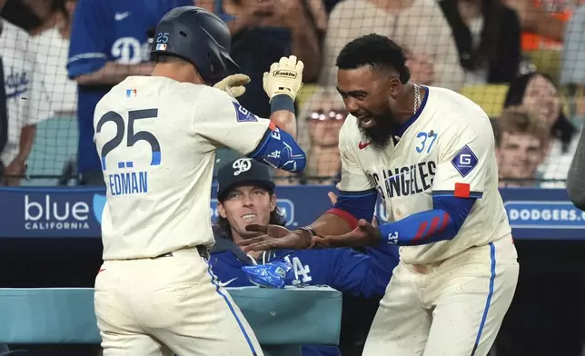 Los Angeles Dodgers' Tommy Edman is congratulated by Teoscar Hernández after hitting a solo home run during the fifth inning of a baseball game against the San Francisco Giants, Saturday, Sept. 20, 2025, in Los Angeles. (AP Photo/Mark J. Terrill)