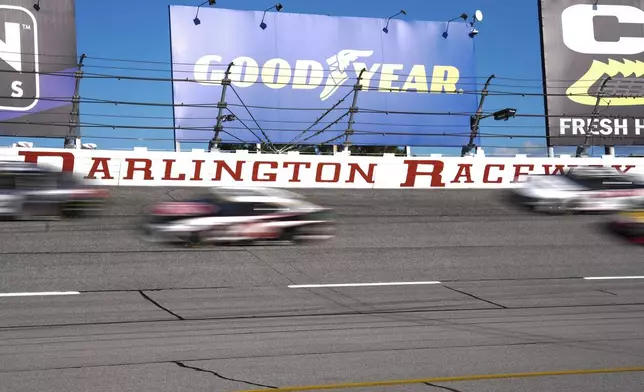 A pack of cars drives through Turn 1 during a NASCAR Cup Series auto race at Darlington Raceway, Sunday, Aug. 31, 2025, in Darlington, S.C. (AP Photo/Matt Kelley)