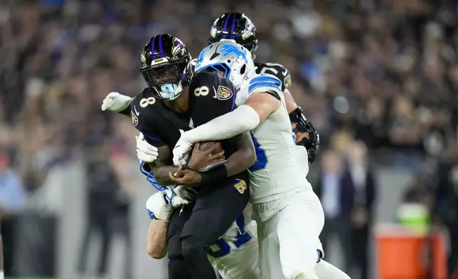 Baltimore Ravens quarterback Lamar Jackson (8) is brought down by Detroit Lions linebacker Trevor Nowaske, right, and defensive end Aidan Hutchinson, bottom, during the second half of an NFL football game Monday, Sept. 22, 2025, in Baltimore. (AP Photo/Stephanie Scarbrough)