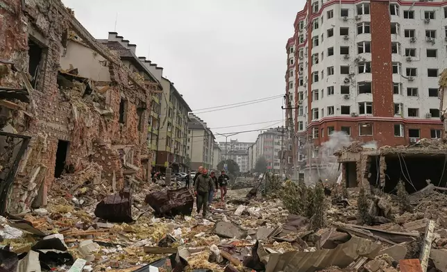 People walk near apartment buildings damaged after a Russian attack in Kyiv, Ukraine, Sunday, Sept. 28, 2025. (AP Photo/Efrem Lukatsky)