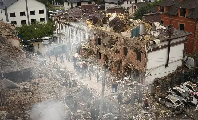 People seen at the site of an apartment building destroyed during a Russian attack in Kyiv, Ukraine, Sunday, Sept. 28, 2025. (AP Photo/Efrem Lukatsky)