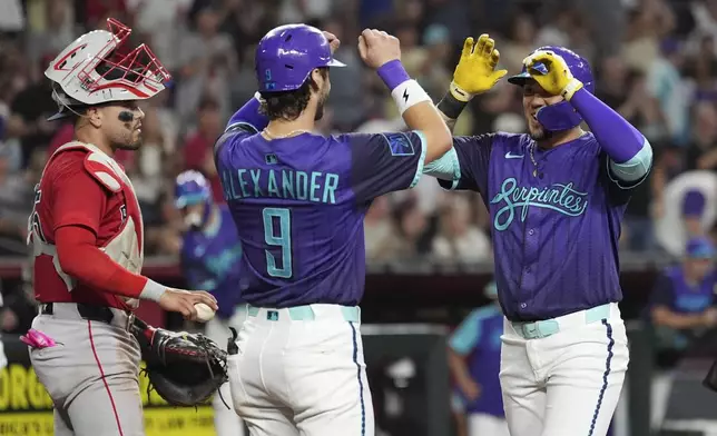 Arizona Diamondbacks' Ildemaro Vargas, right, celebrates his three-run home run with Diamondbacks' Blaze Alexander (9) as Boston Red Sox catcher Carlos Narváez, left, pauses at home plate during the third inning of a baseball game Friday, Sept. 5, 2025, in Phoenix. (AP Photo/Ross D. Franklin)