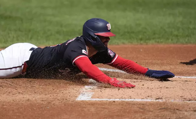 Washington Nationals' Luis Garcia Jr. slides into home plate and scores on a triple hit by Daylen Lile during the second inning of a baseball game against the Miami Marlins at Nationals Park, Monday, Sept. 1, 2025, in Washington. (AP Photo/Jess Rapfogel)