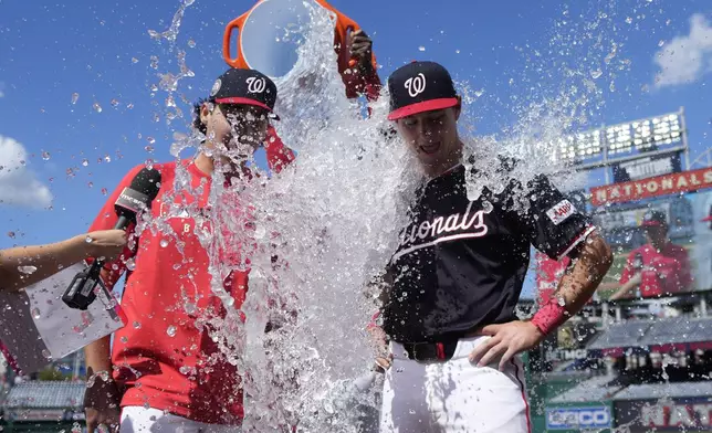 Washington Nationals starting pitcher Andrew Alvarez, left, and catcher CJ Stubbs get doused with water by Josh Bell after securing a win against the Miami Marlins in their major league debuts at Nationals Park, Monday, Sept. 1, 2025, in Washington. (AP Photo/Jess Rapfogel)