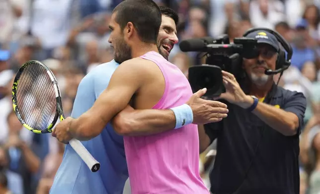 Novak Djokovic, of Serbia, hugs Carlos Alcaraz, of Spain, after losing to Alcaraz in the men's singles semifinals of the U.S. Open tennis championships, Friday, Sept. 5, 2025, in New York. (AP Photo/Kirsty Wigglesworth)