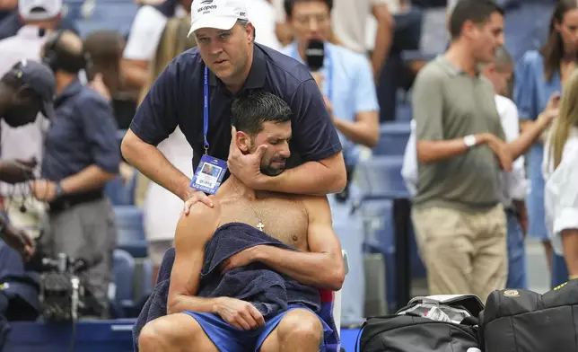 Athletic trainer Clay Sniteman works on Novak Djokovic, of Serbia, between sets against Carlos Alcaraz, of Spain, during the men's singles semifinals of the U.S. Open tennis championships, Friday, Sept. 5, 2025, in New York. (AP Photo/Kirsty Wigglesworth)