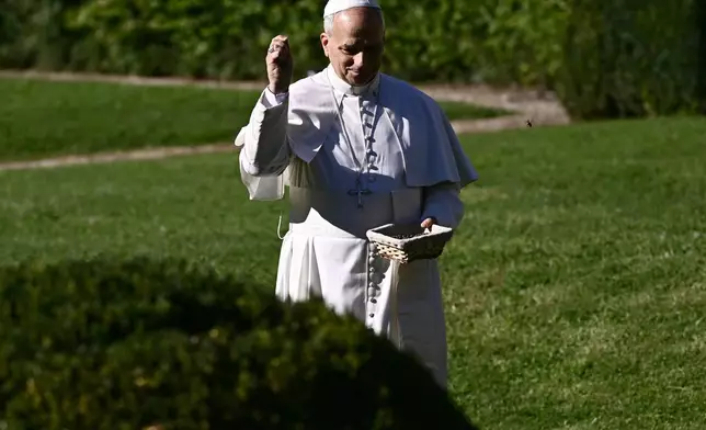 Pope Leo XIV feeds fishes of a pond during the inauguration of the "Borgo Laudato Si'" Advanced Training Center, at the papal summer residence in Castel Gandolfo, Italy, Friday Sept. 5, 2025. (Filippo Monteforte, Pool via AP)