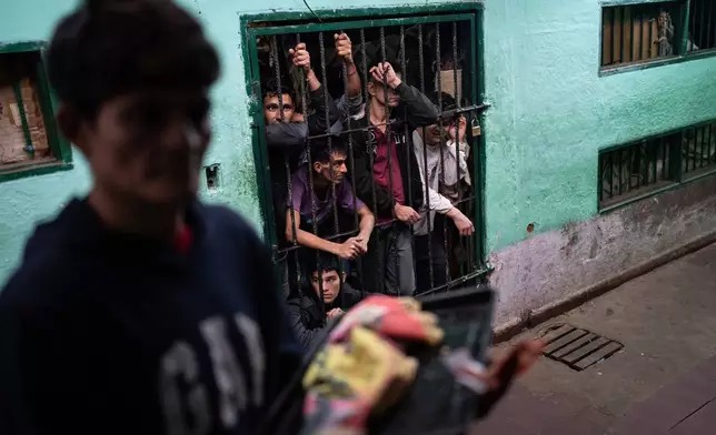 FILE PHOTO GALLERY - Prisoners peer out from their group cell in the late afternoon as another prisoner prepares to enter another group cell at the Regional Penitentiary in Villarica, Paraguay, Aug. 31, 2024. (AP Photo/Rodrigo Abd)