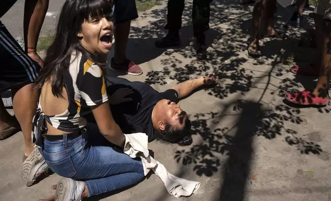 FILE PHOTO GALLERY - Neighbors shout for help while assisting Veronica Lopez, aunt of Máximo Jerez, an 11-year-old boy was killed when a gunman attacked a birthday in the Los Pumitas neighborhood of Rosario, Argentina, March 6, 2023. Lopez fainted during violence that erupted after the death of the boy. (AP Photo/Rodrigo Abd)