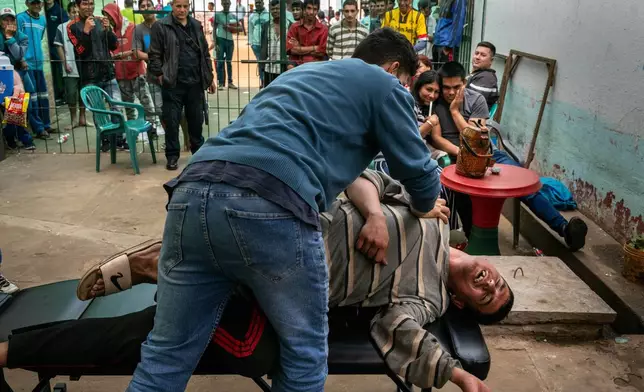 FILE PHOTO GALLERY - An inmate giggles as a volunteer physical therapist provides a free stretching session during visitors day at the Regional Penitentiary in Villarica, Paraguay, Sept. 1, 2024. (AP Photo/Rodrigo Abd)
