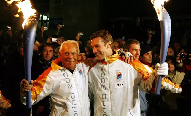 FILE - Italy's fashion designer Giorgio Armani, left, and AC Milan's soccer player Andriy Shevchenko of Ukraine, pose for a photo holding the Olympic torches in Milan, northern Italy, Jan. 29, 2006. (AP Photo/Luca Bruno, File)